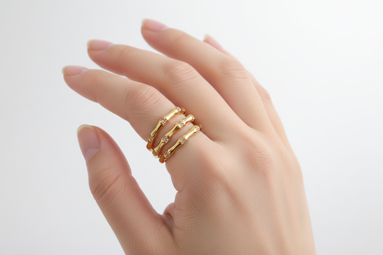Hand wearing two gold rings on a light background