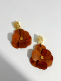 Pair of brown floral earrings with gold accents on a light gray background