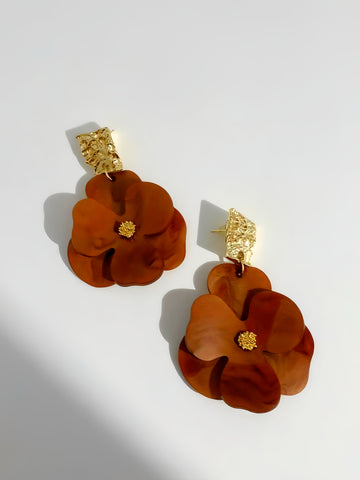 Pair of brown floral earrings with gold accents on a light gray background