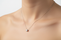 Silver necklace with a small round pendant on a light beige background