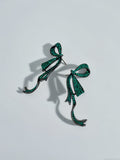 Pair of green bow-shaped earrings on a light gray background