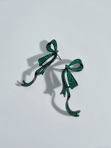 Pair of green bow-shaped earrings on a light gray background
