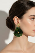 Green floral earrings with gold accents on a light gray background