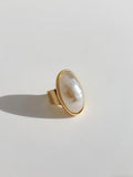 Gold ring with a large pearl on a light gray background