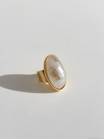 Gold ring with a large pearl on a light gray background