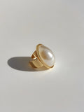 Gold ring with a large pearl on a light gray background